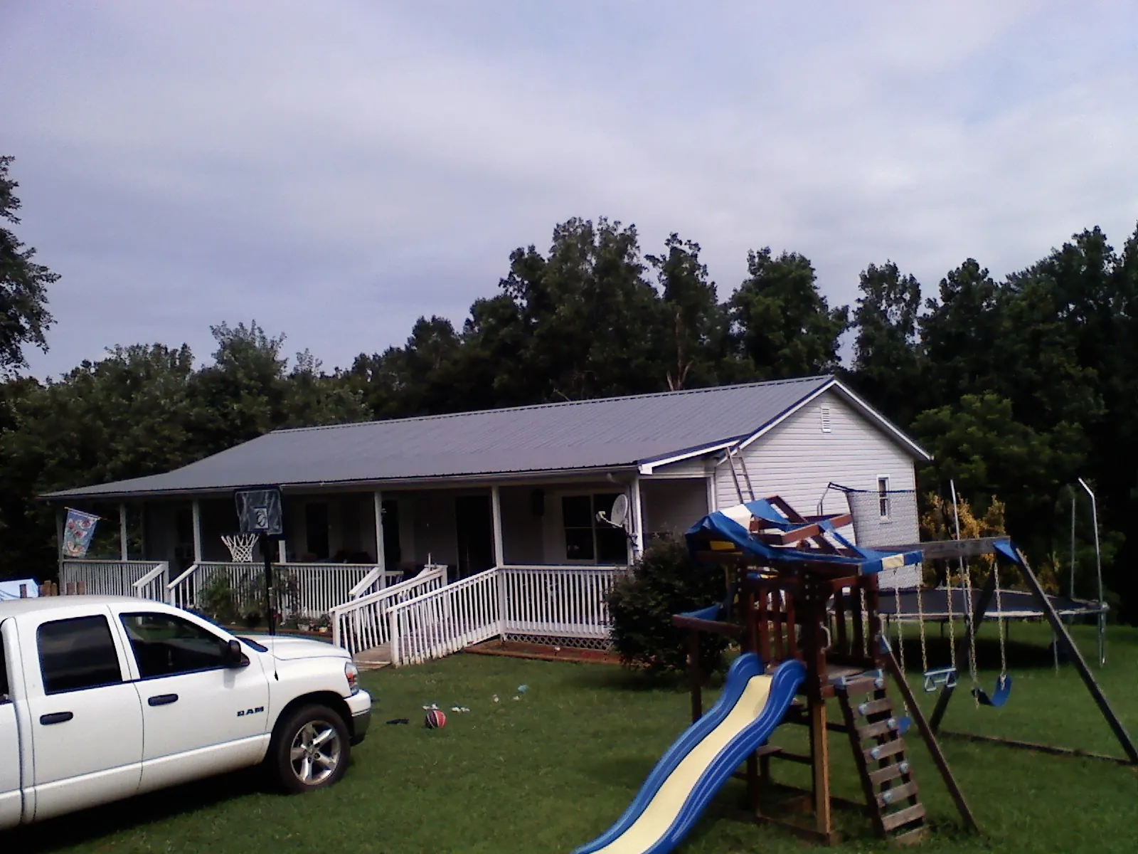 Dark metal roof on a country home with a full length front porch in Atwater