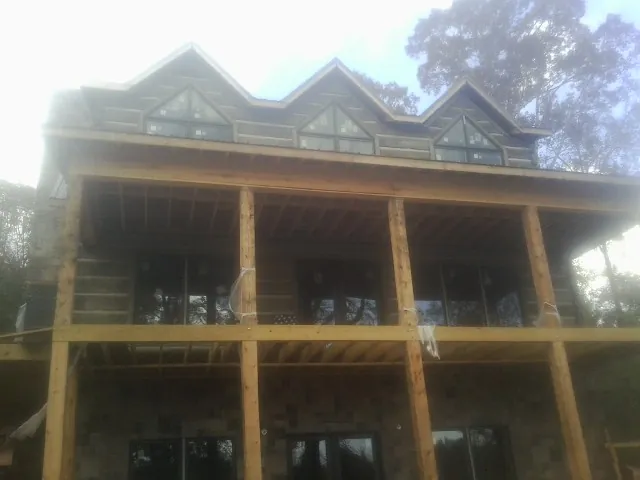 Dormers and porch framing on a large log home under construction — Roof Coating work by our crew in Atwater