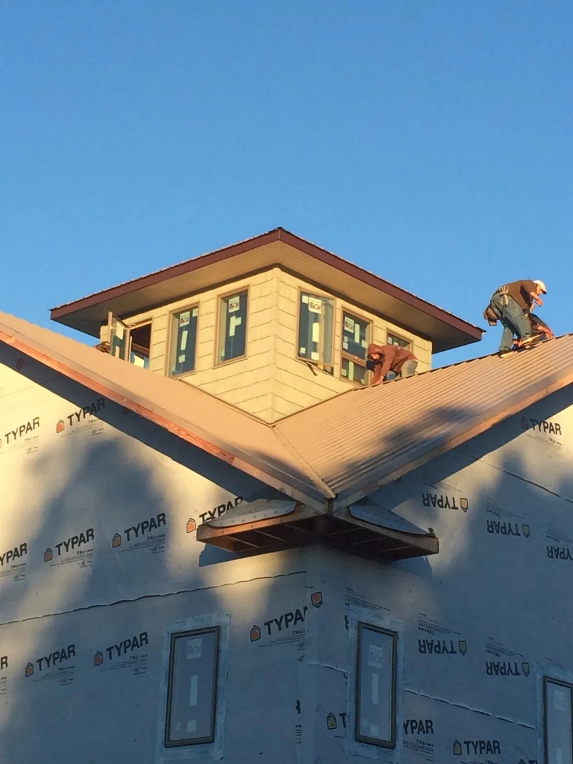 Roofers working around a rooftop cupola on a new metal roof at sunset — Roof Waterproofing in Atwater by Roofing Brothers